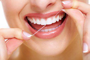 Woman holding dental floss in her hands flossing her teeth