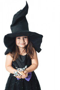 little girl witch costume holding Halloween candy