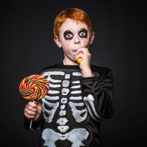 boy dressed in skeleton costume eating Halloween candy