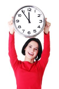 Happy young woman holding a large clock over her head