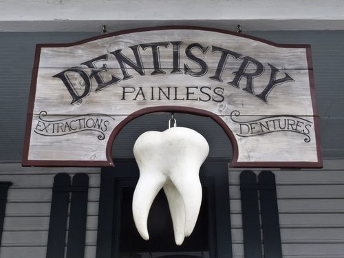 Vintage sign with giant tooth hanging in front of dentist office-img-blog