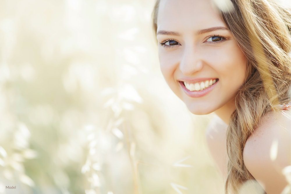 Woman smiling with straight teeth that is possible with Invisalign®.