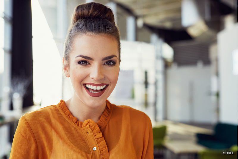 Woman with her hair in a bun, showing off her big, beautiful smile.