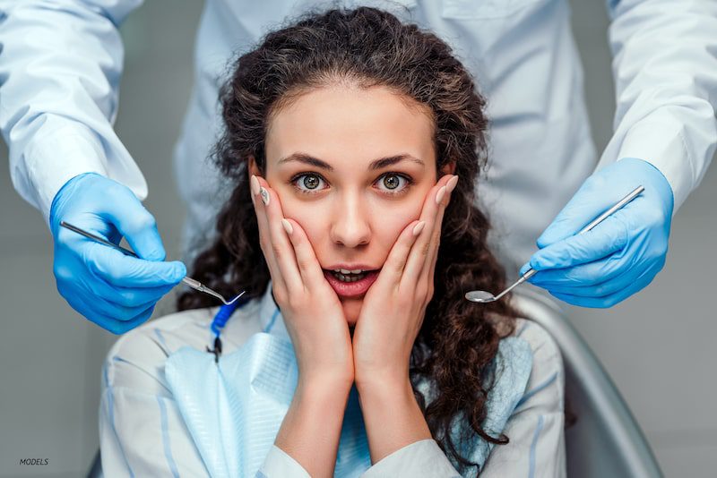 Nervous woman with hands on her cheeks at dentist