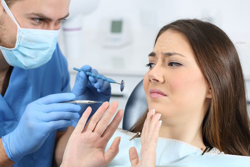 A female dental patient is afraid of an exam.