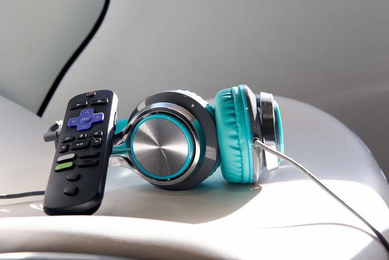 Headphones and a remote control sit on a chair.