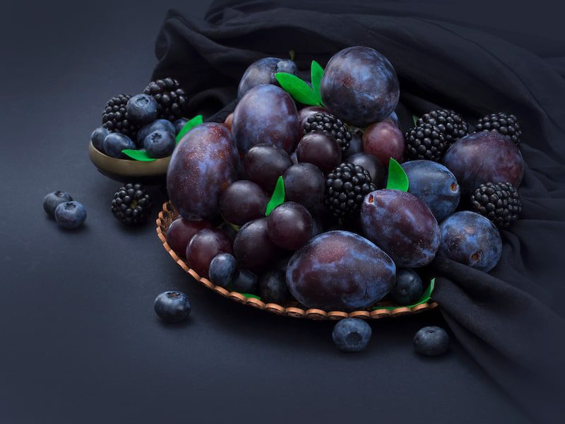Berries and other dark fruits in a bowl.