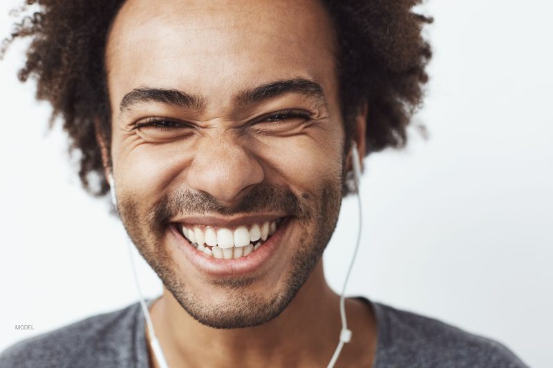 A happy man with white teeth is smiling.