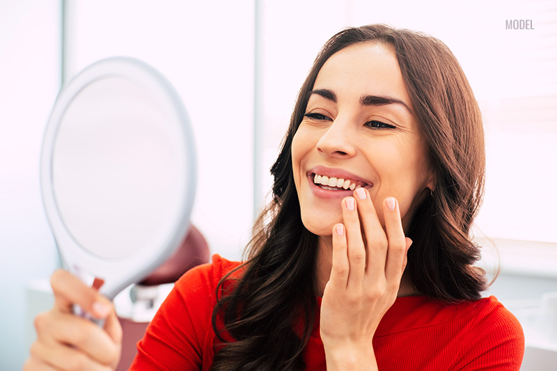 Woman looking in the mirror with hand over her teeth