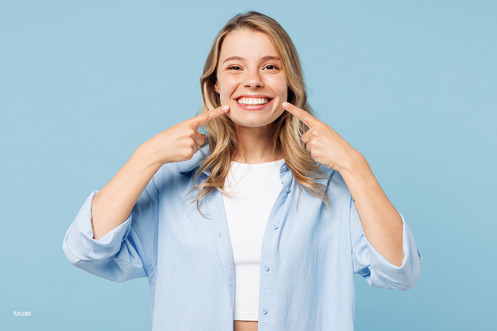 Young woman smiling pointing at her teeth