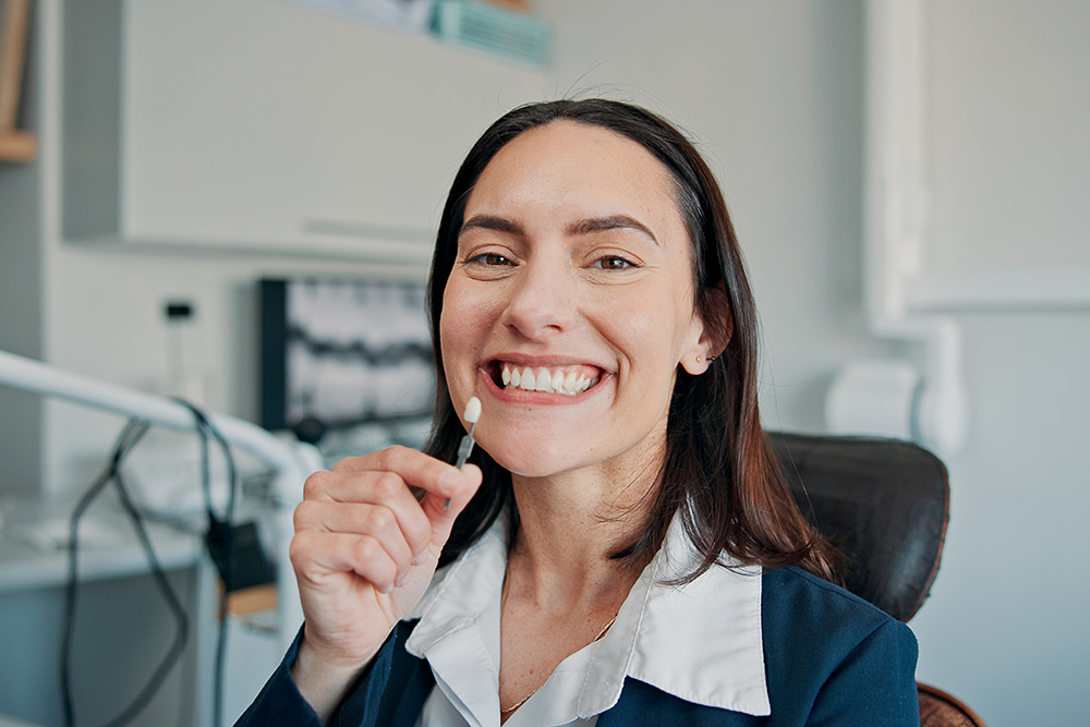 Woman holding a dental implant against her teeth