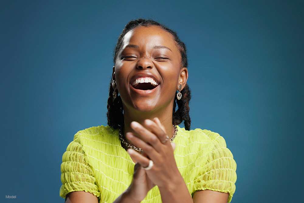 Woman in a yellow shirt clapping and laughing